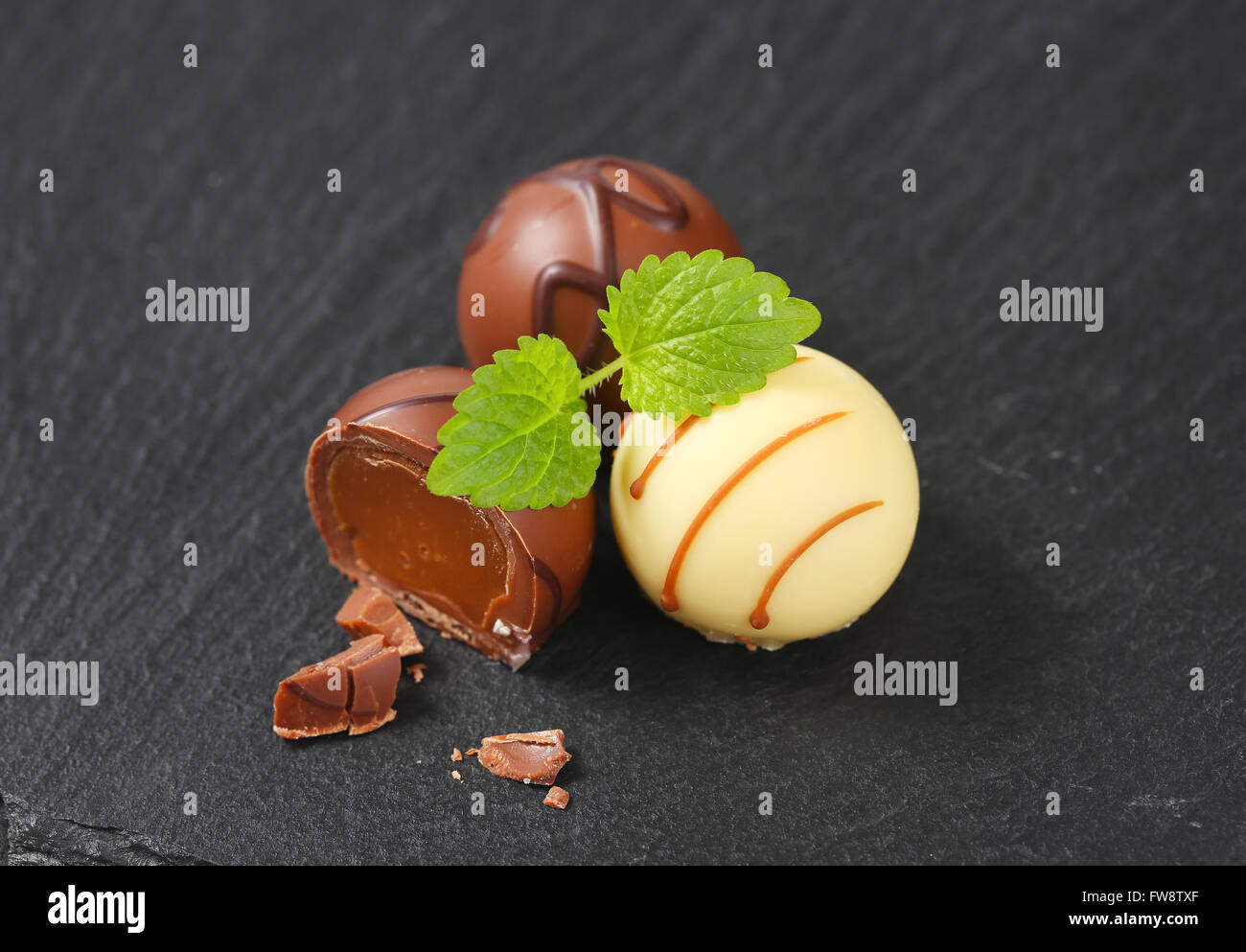 Due e mezza belga praline di cioccolato su sfondo nero Foto Stock