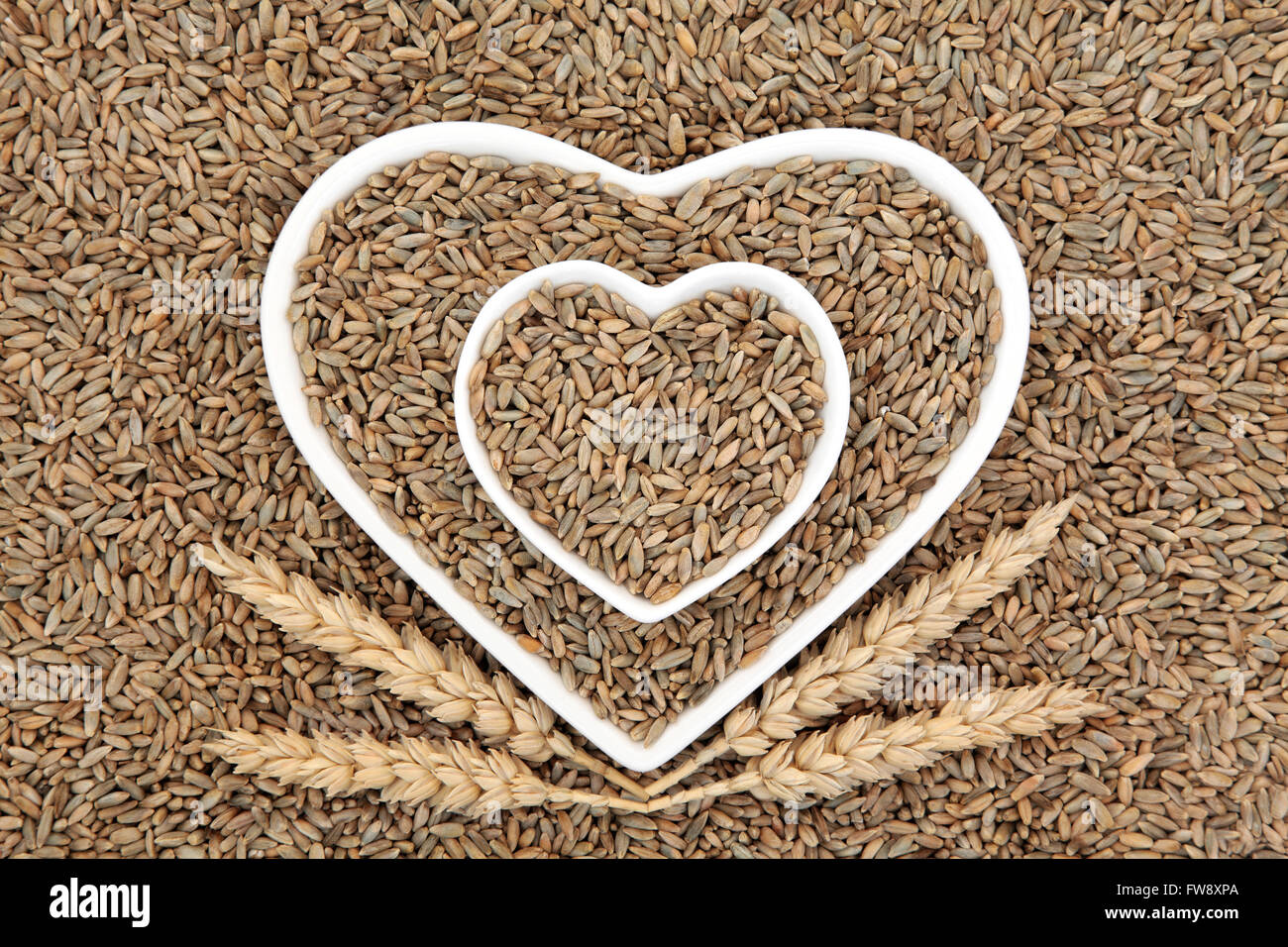 Segale grano in forma di cuore ciotole con guaine di grano formando un abstract background. Foto Stock