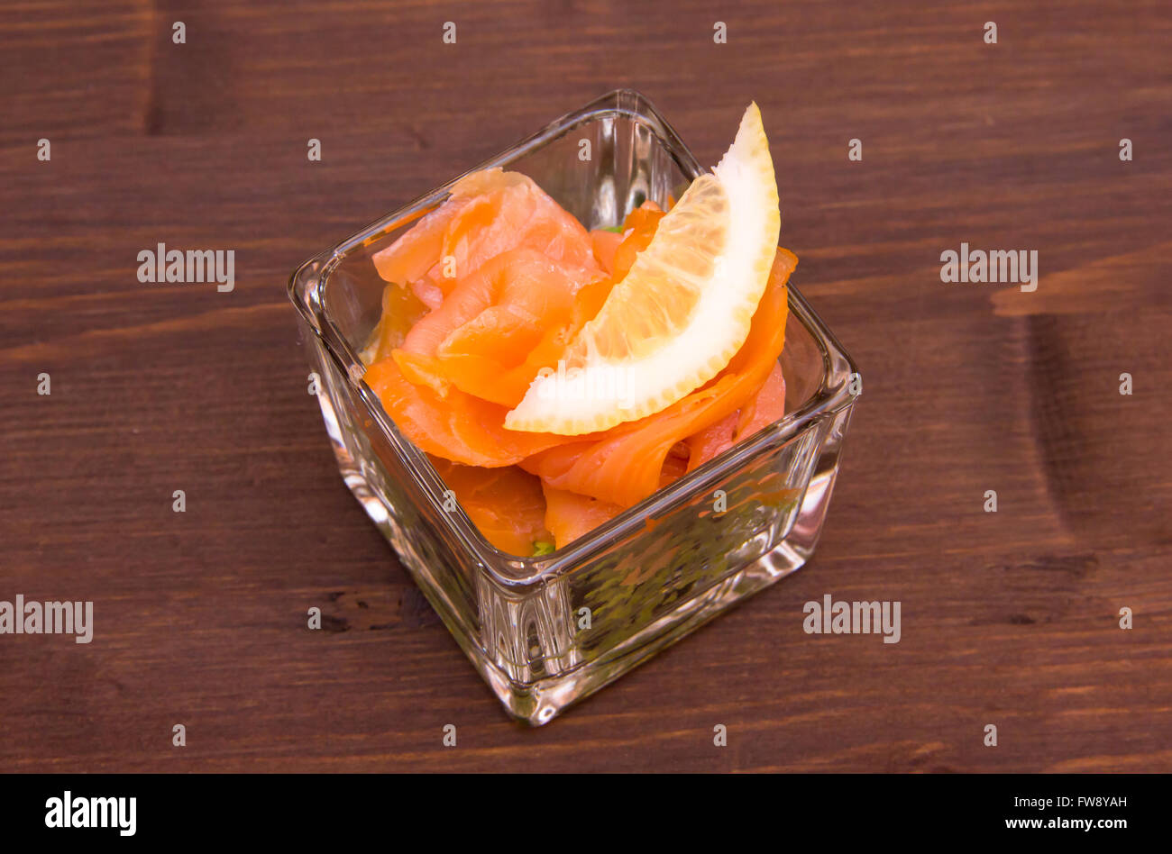 Avocado e salmone affumicato su vetro quadrato sul tavolo in legno visto da sopra Foto Stock