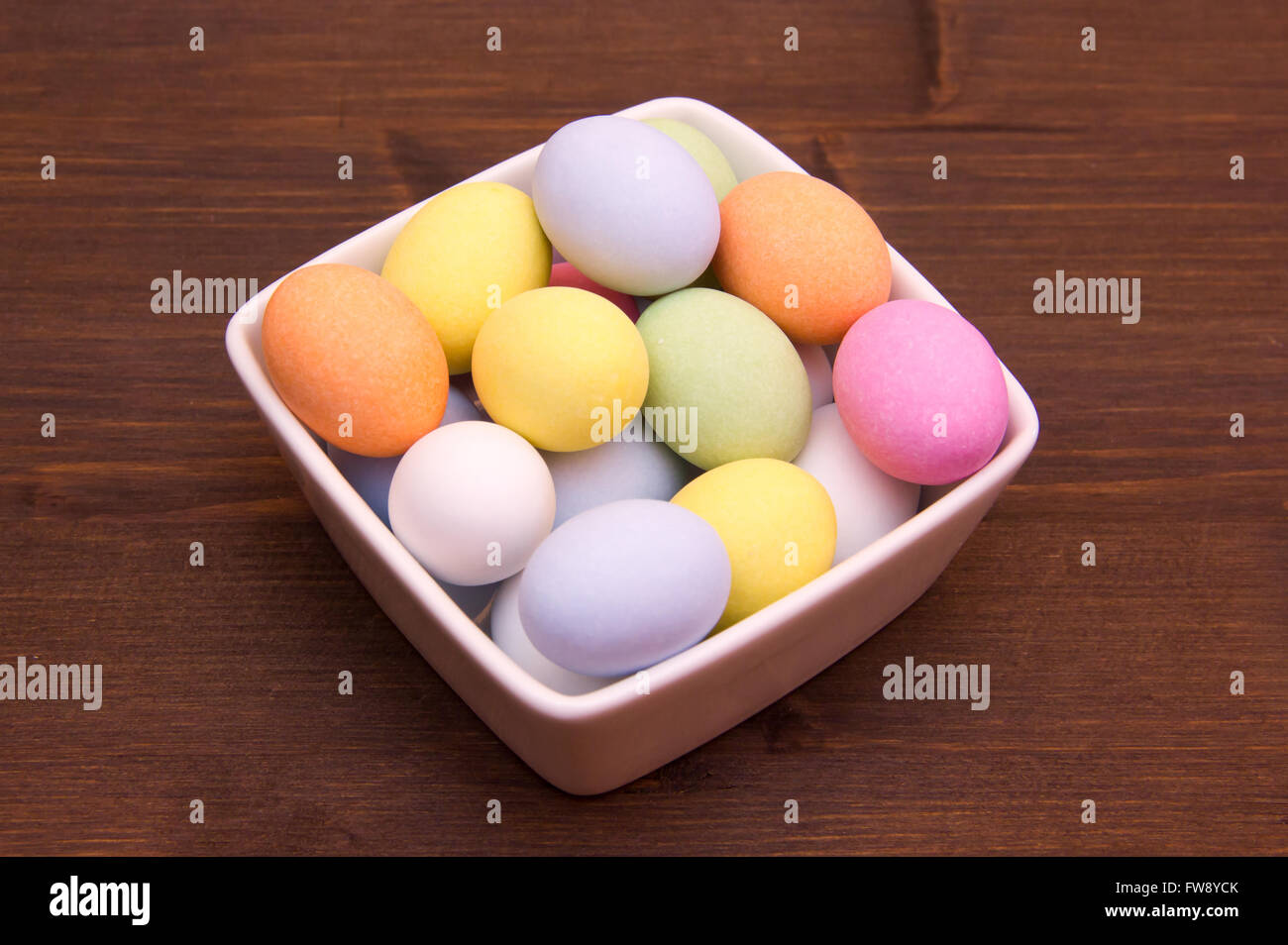 Uova colorate su un recipiente quadrato sul tavolo di legno Foto Stock