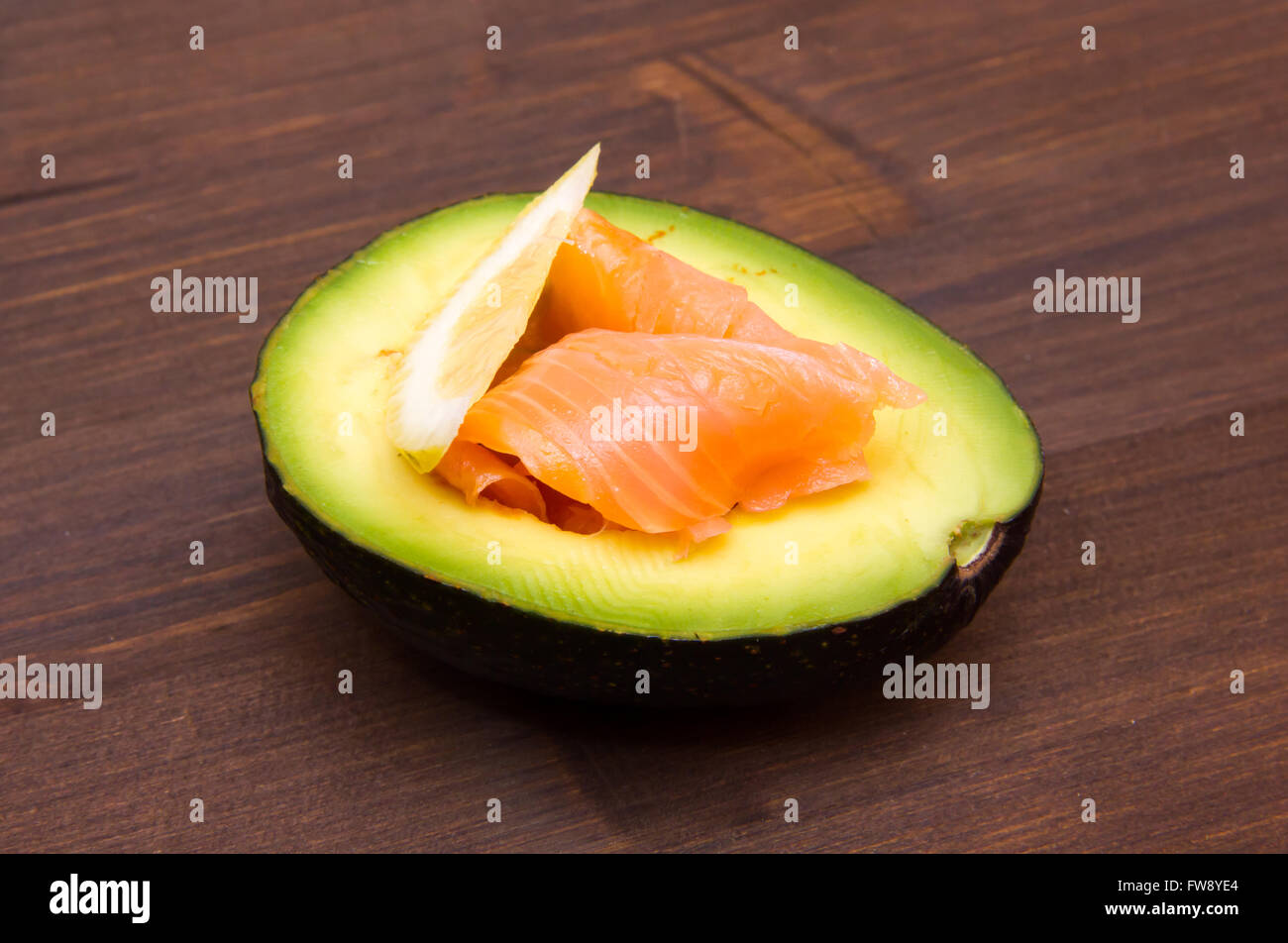 Mezz'avocado con salmone affumicato su un tavolo di legno Foto Stock