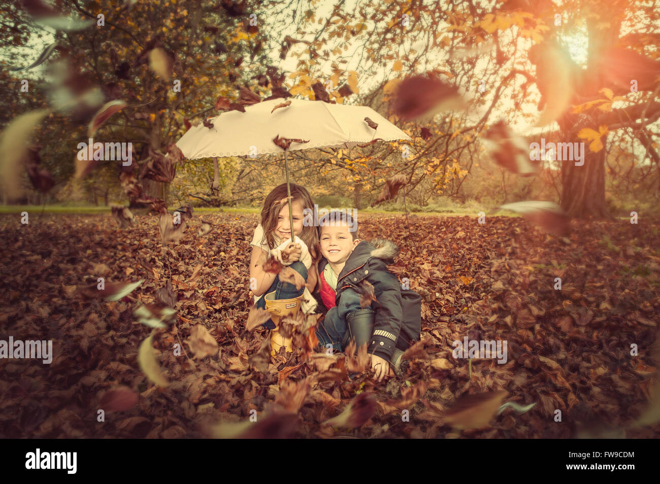 Due bambini sotto ombrellone in autunno park Foto Stock