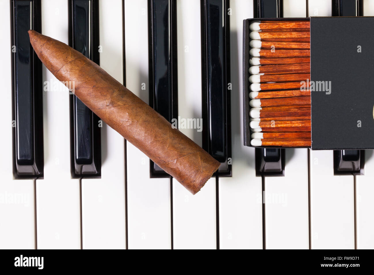 Dettaglio della tastiera di pianoforte e sigari di lusso Foto Stock