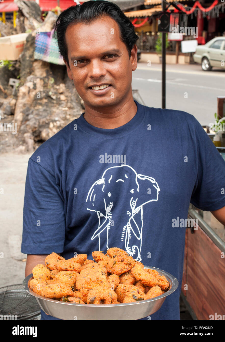 Uomo di Maurizio con coppa di gateaux piment in Mauritius. Foto Stock