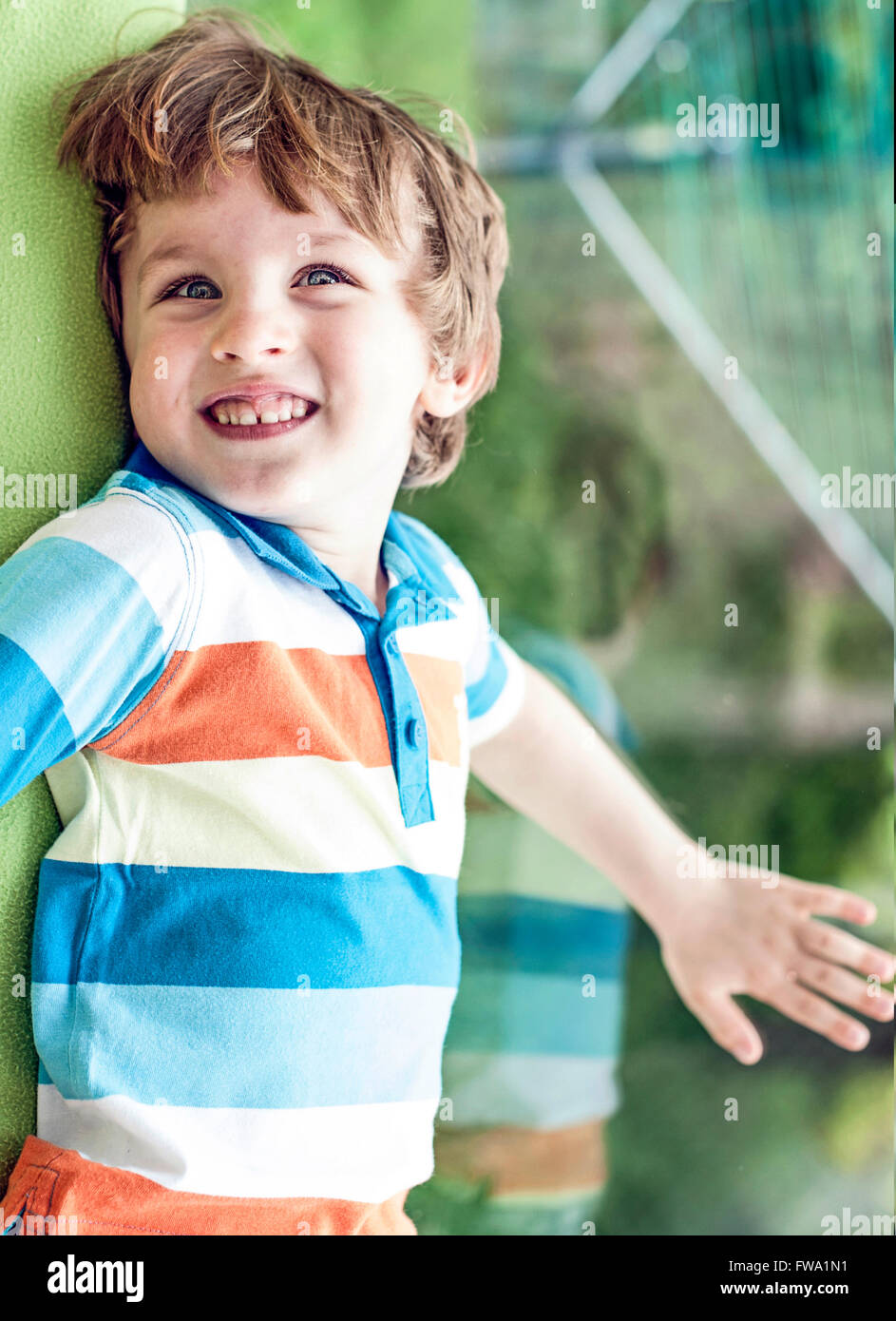 Un piccolo ragazzo felici giocando dalla finestra in casa Foto Stock