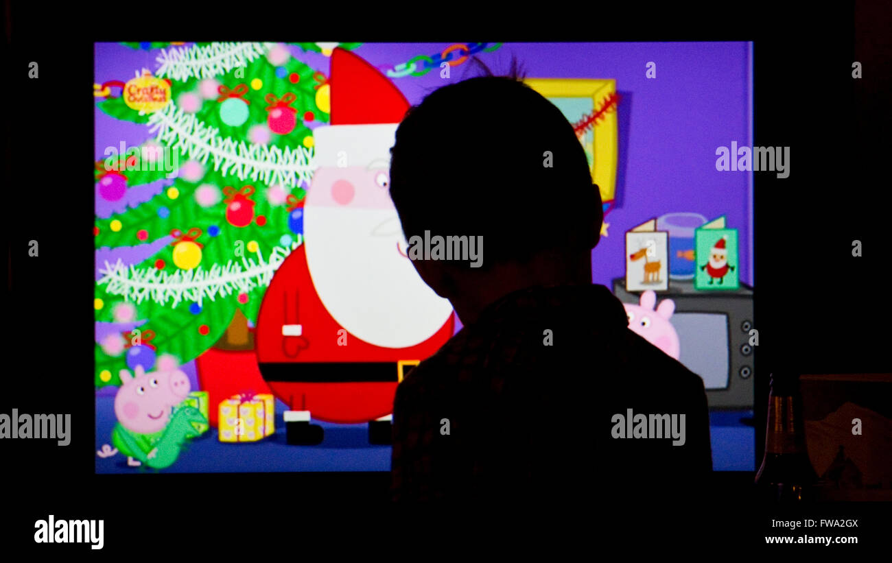 Silhouette di un bambino di tre anni ragazzo la visione di un programma televisivo a Natale Foto Stock