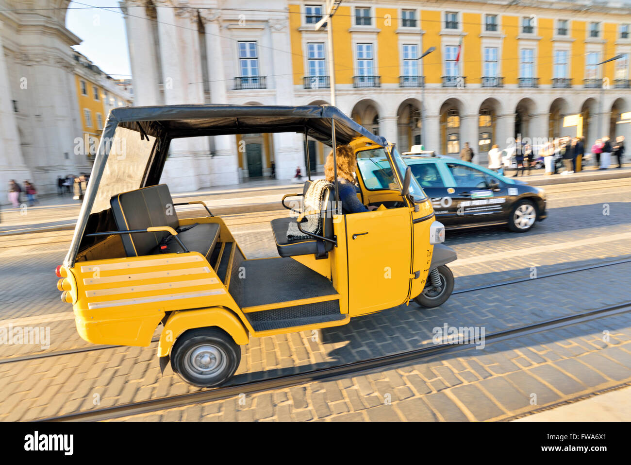 Il Portogallo, Lisbona: Giallo Tuc-Tuc passando il Taxi a Praca do Comercio Foto Stock