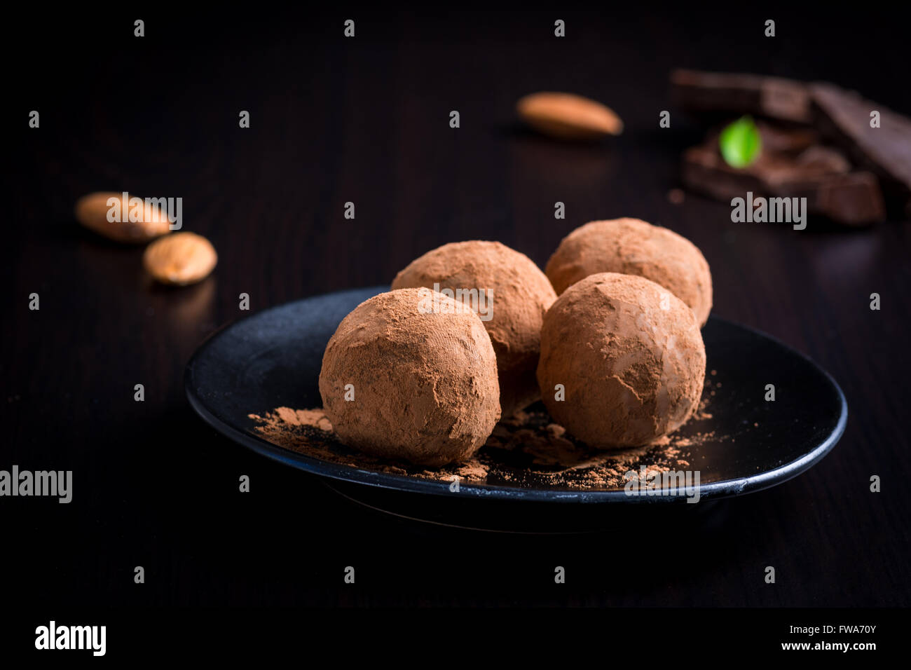 In casa tartufi di cioccolato sulla piastra nera su sfondo nero. Dessert di lusso, vellutata tartufi di cioccolato Foto Stock