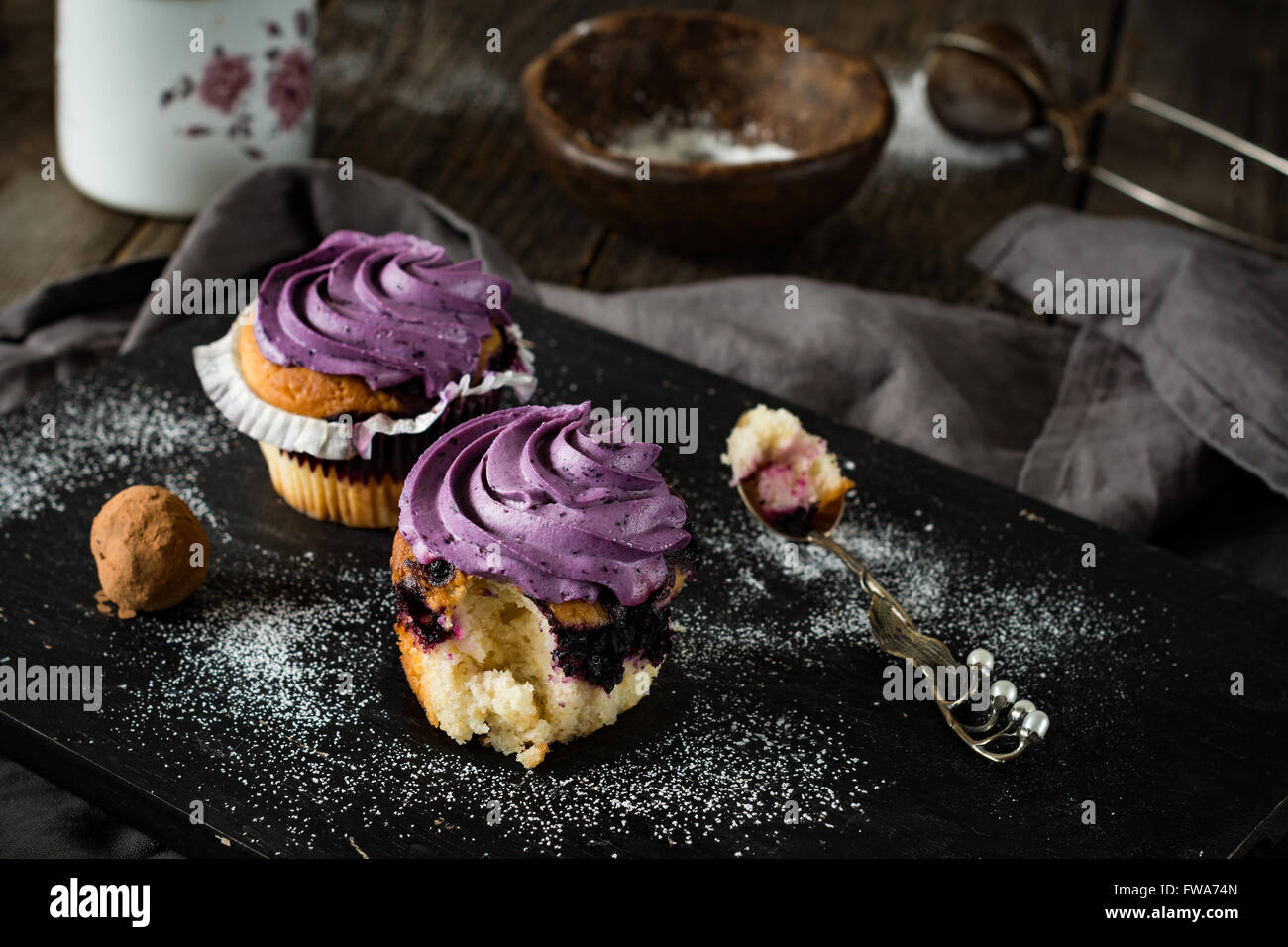 Mirtillo tortine con viola crema al burro nero sulla tavola di legno. Alimentare la vita ancora, stile rustico Foto Stock