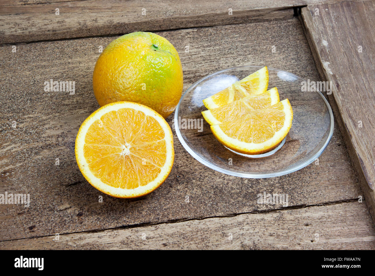 Arancio tagliate a metà e affettate sottilmente sulla vecchia tabella legno Foto Stock