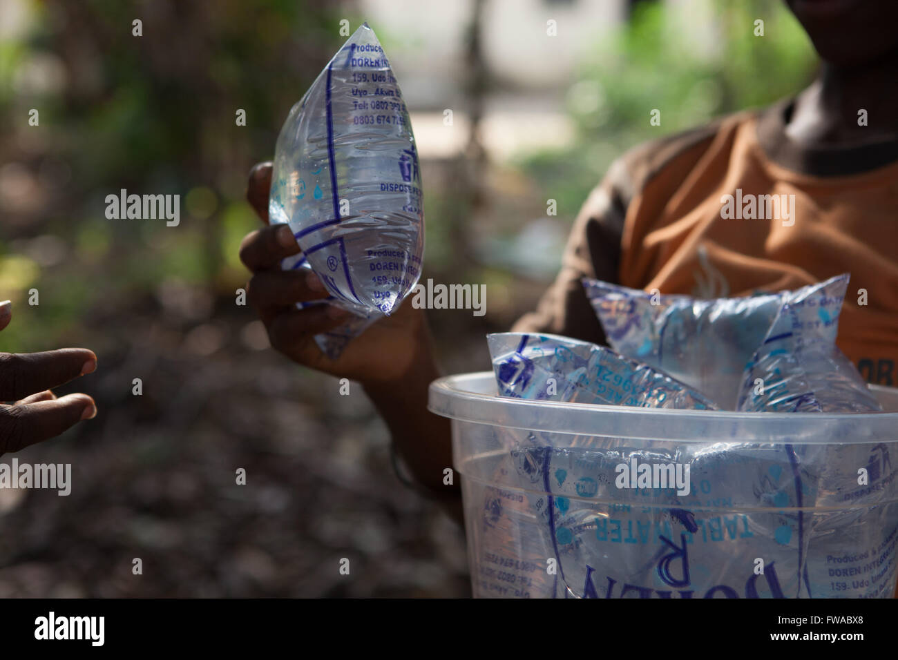 Un ragazzo la vendita di bustine di acqua purificata per le strade della Nigeria, Africa Foto Stock