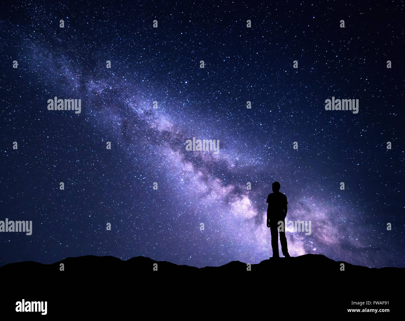 Paesaggio con viola Via Lattea. Cielo notturno con stelle e la silhouette di un uomo felice sulla montagna. Bella universo. Spazio Foto Stock