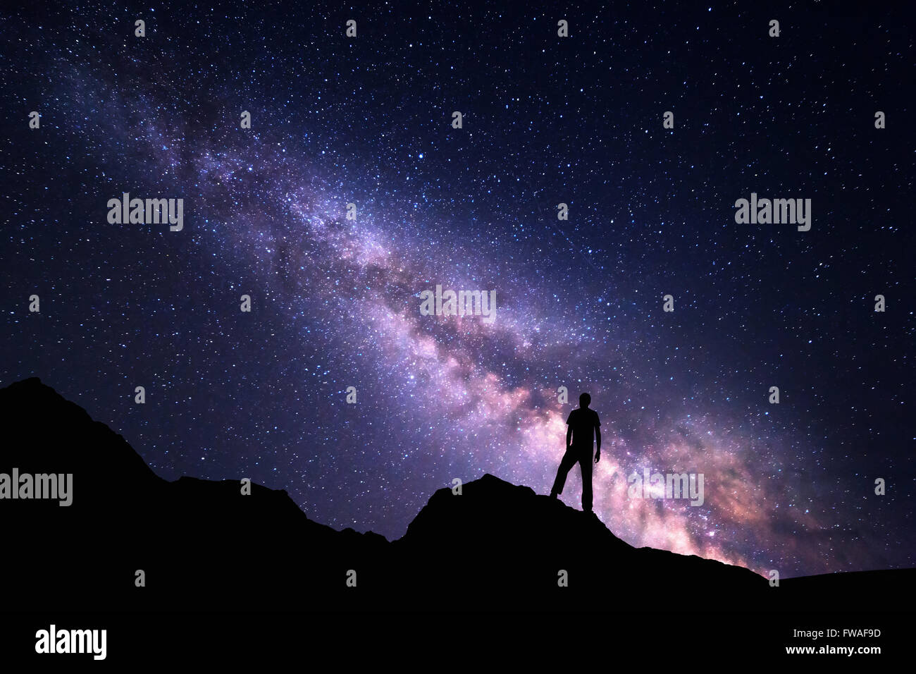 Paesaggio con Via Lattea. Cielo notturno con stelle e la silhouette di un uomo felice sulla roccia. Bella universo. Sfondo spazio Foto Stock