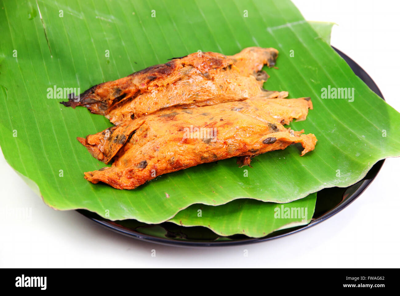 Pesce al Curry in foglie di banano grigliate con il calore su sfondo bianco Foto Stock