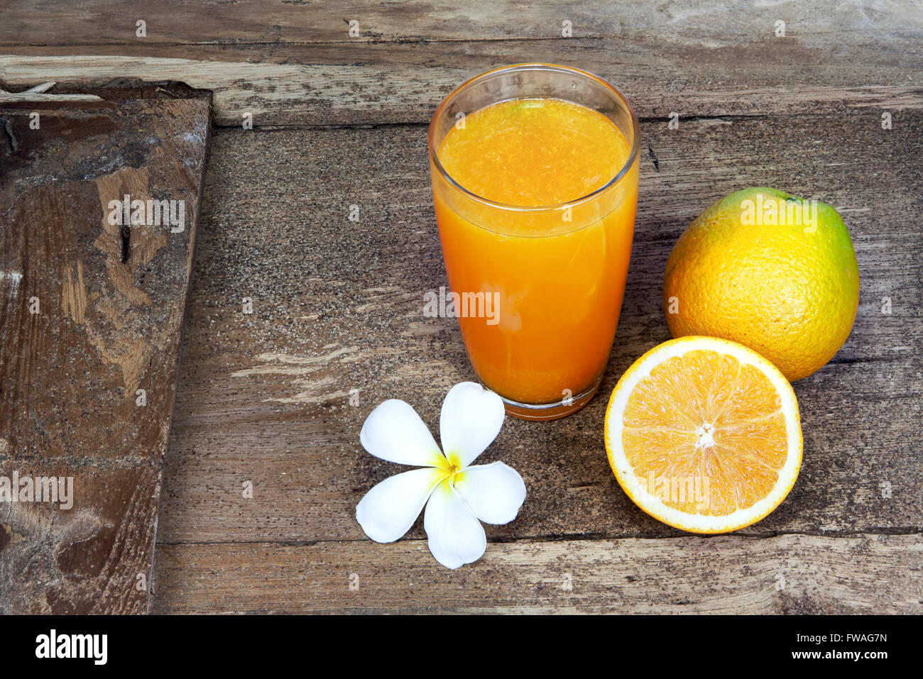 Arancio tagliate a metà e affettate sottilmente e succo d'arancia fresco in vetro sul vecchio tavolo legno Foto Stock
