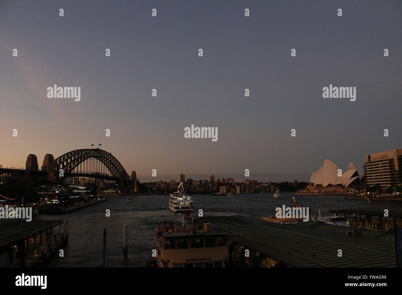 Sydney Harbour Bridge e Opera House dopo il tramonto visto da la stazione dei treni di Circular Quay e. Foto Stock