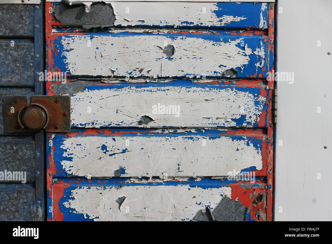 Peeling rosso, bianco e blu della vernice sul vecchio metallo porta di garage Foto Stock