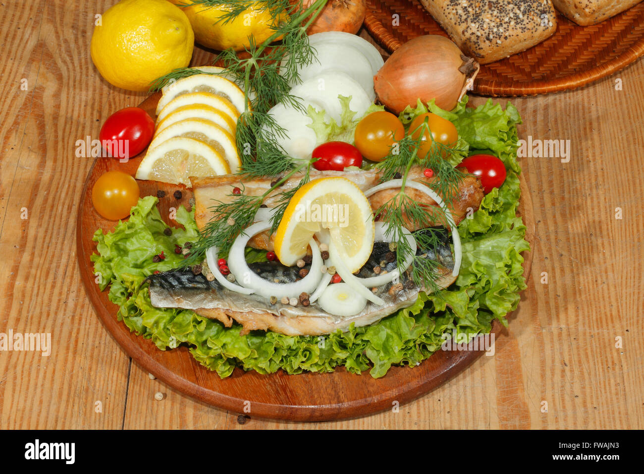 Sgombro affumicato di filetto con insalata, limone, cipolle, pomodori, guarnito con aneto su una cucina in legno board Foto Stock