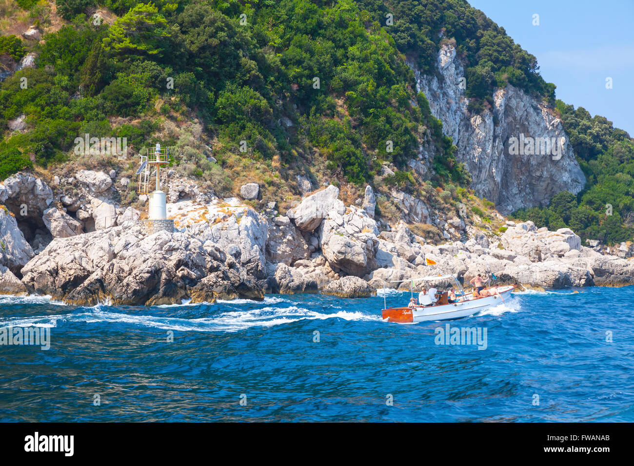 Capri, Italia - 14 agosto 2015: piccolo piacere motoscafo con turisti va vicino a rocce costiere di isola di Capri, Italia Foto Stock