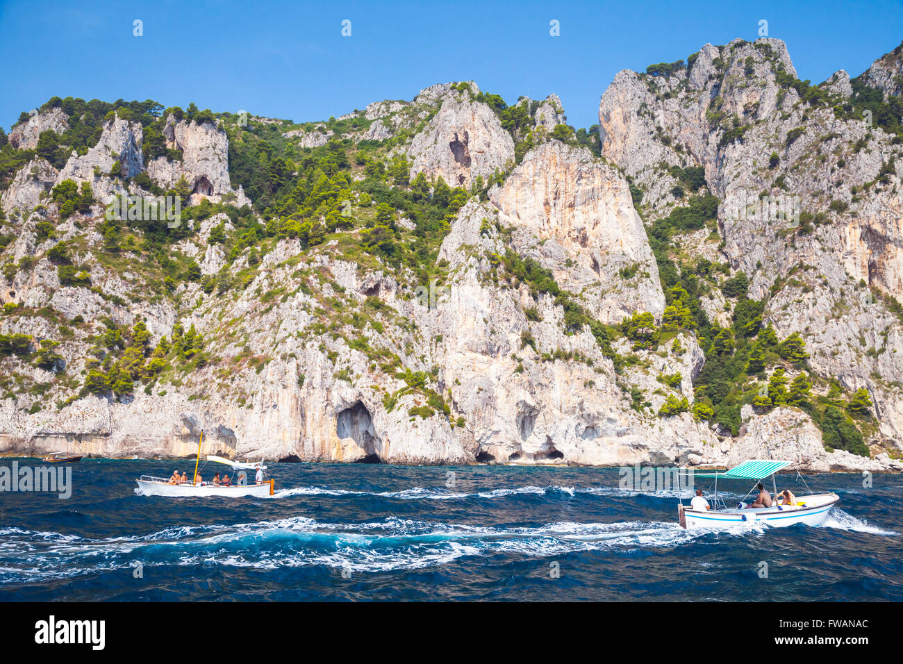 Capri, Italia - 14 agosto 2015: il piacere di piccole barche a motore con i normali turisti andare vicino a rocce costiere di isola di Capri, Italia Foto Stock