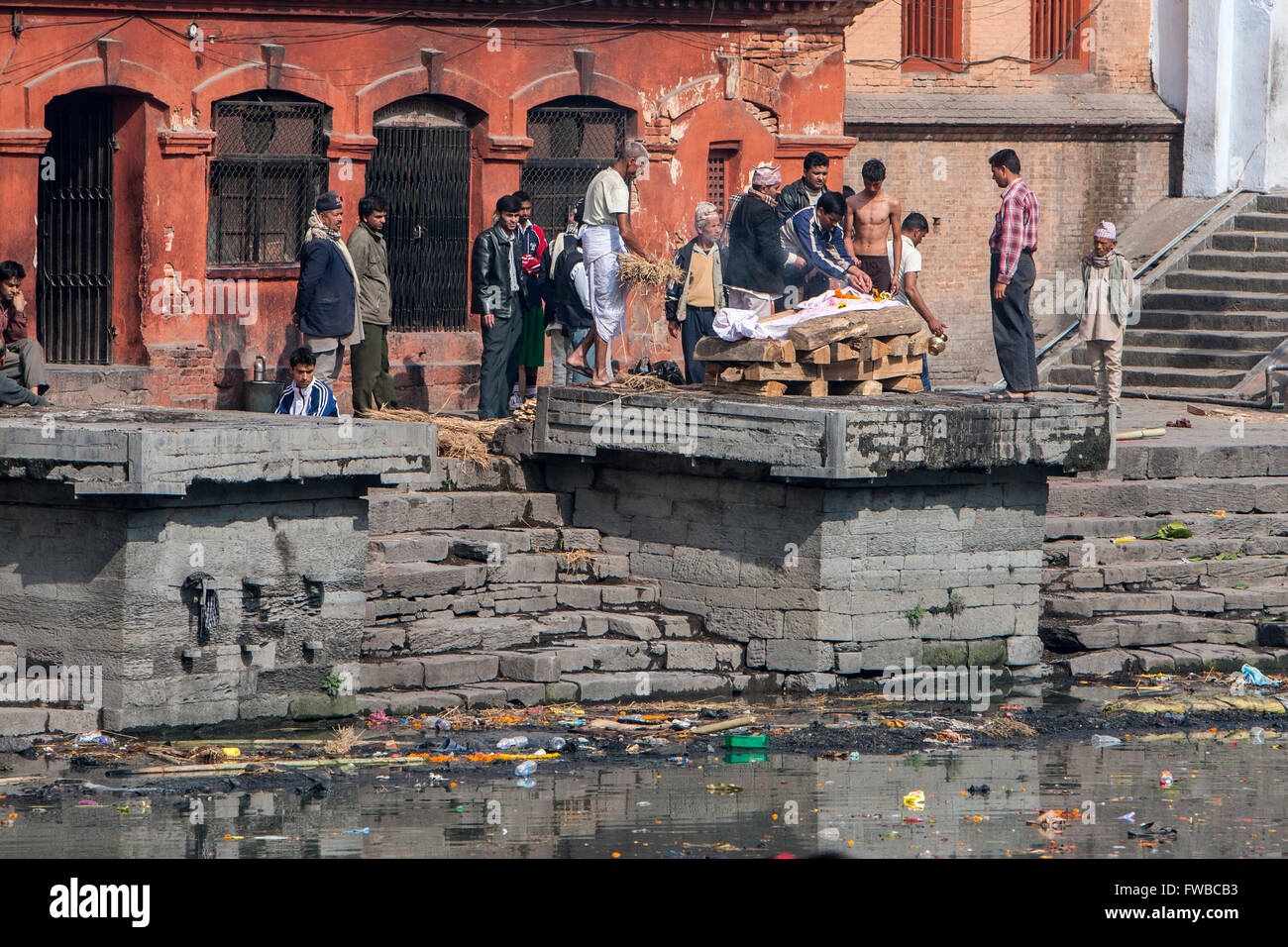 Il Nepal, Pashupatinath. Fasi di cremazione. Con il cadavere avvolto in un foglio, i membri della famiglia preparare alla luce del fuoco. Foto Stock