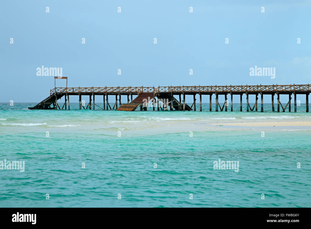 Il molo di legno su una spiaggia tropicale con turchesi acque cristalline, isola di Zanzibar Foto Stock