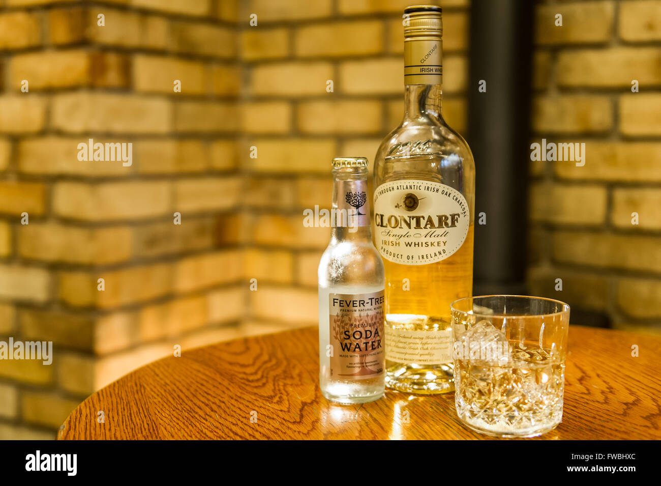 Una bottiglia di Clontarf Single Malt Whiskey irlandese con un imbottigliatore di Fever-Tree Soda Water e un bicchiere di whiskey con cubetti di ghiaccio. Foto Stock