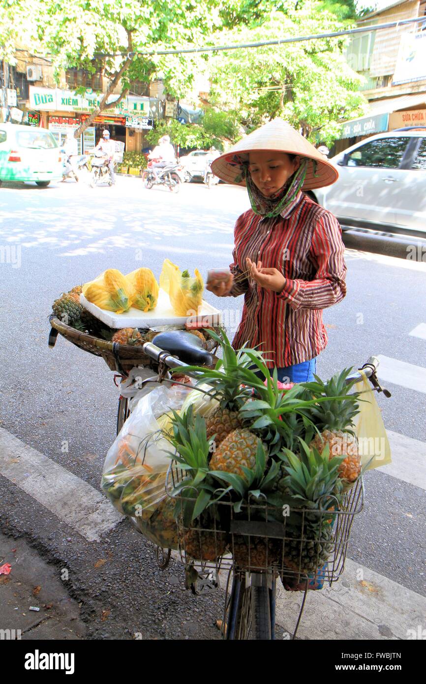 Signora vietnamita vendono frutta fresca dalla sua bicicletta nel quartiere vecchio di Hanoi, Vietnam Asia Foto Stock