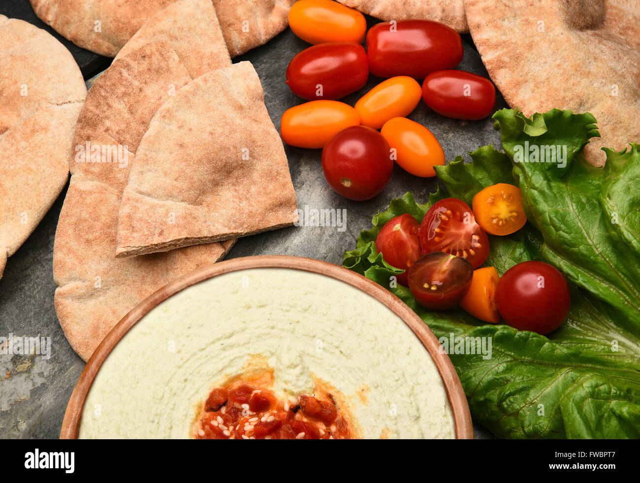 Vista superiore del pane pita, edamame hummus e medley i pomodori su una tavola di ardesia. Foto Stock