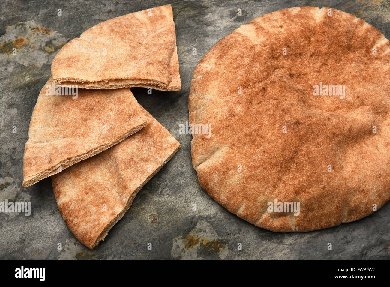 Vista dall'alto di un filone di pane pita e tre pita cunei su una tavola di ardesia. Foto Stock