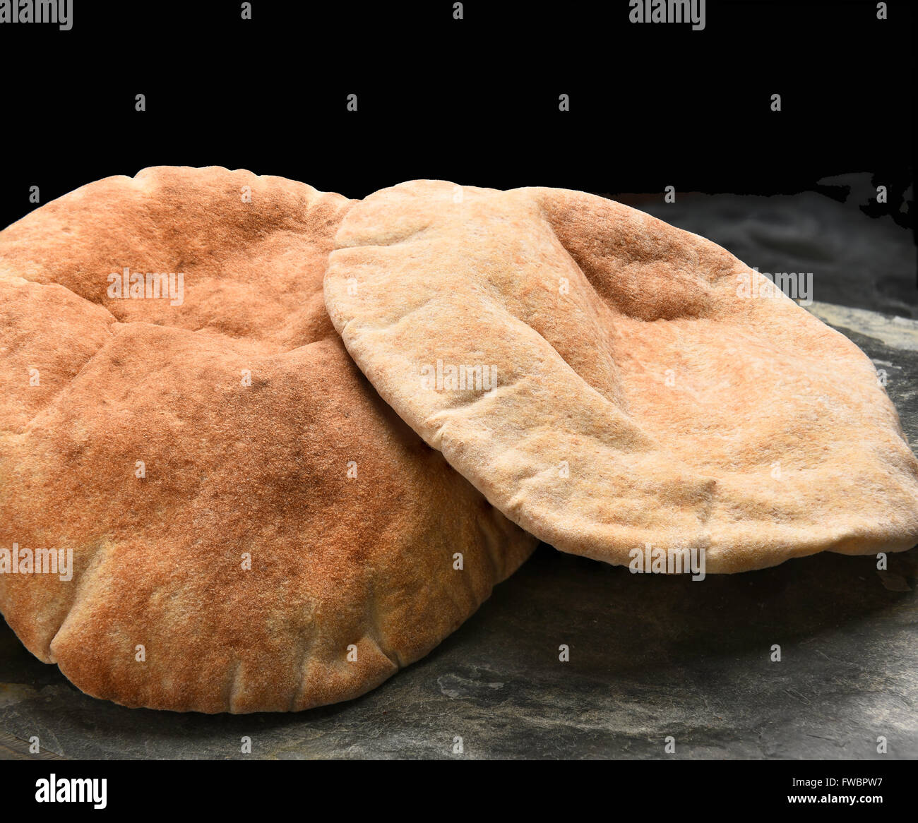 Primo piano di pani di pita il pane su una superficie di ardesia e sfondo nero. Foto Stock