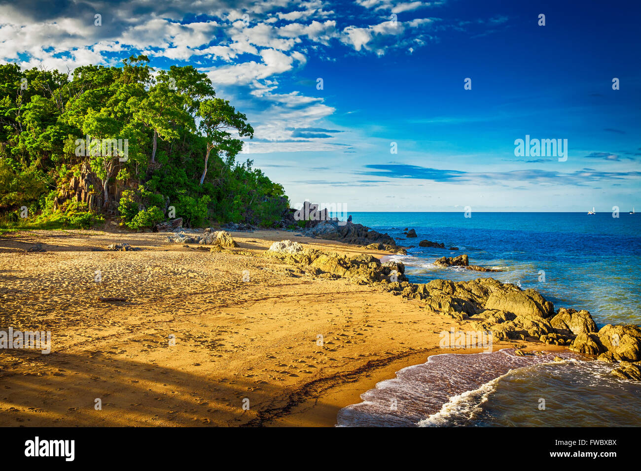 La spiaggia principale di Palm Cove con rocce e alberi durante il tramonto, Australia Foto Stock