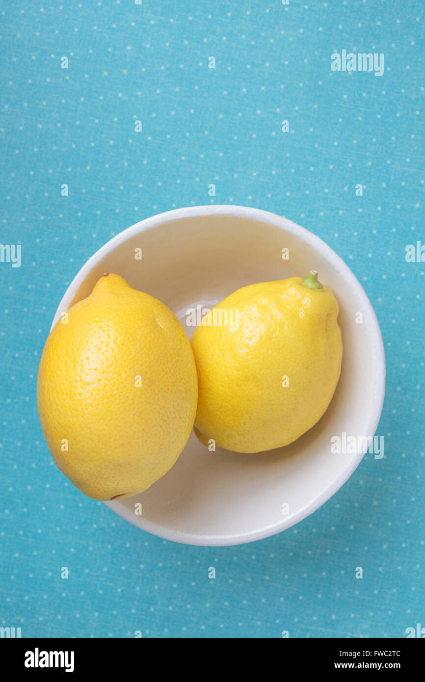 Due limoni giallo in una ciotola bianca e blu ripresa dall'alto. Foto Stock