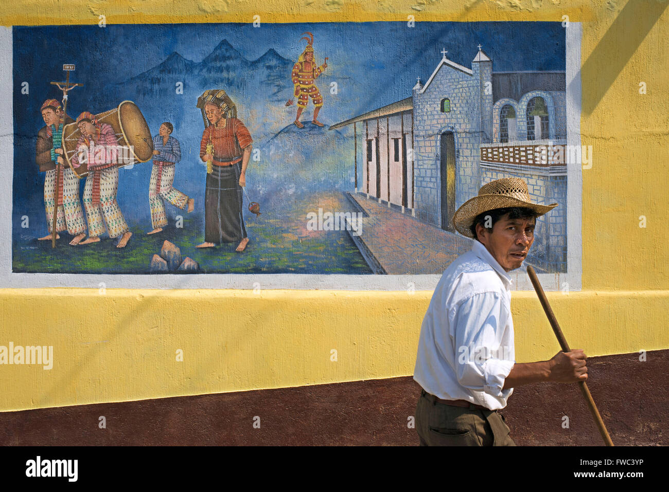 Local uomo a camminare di fronte a un muro dipinto in San Juan La Laguna, Sololá, Guatemala. Maya tradizionale arte pittorica a Santiago Foto Stock