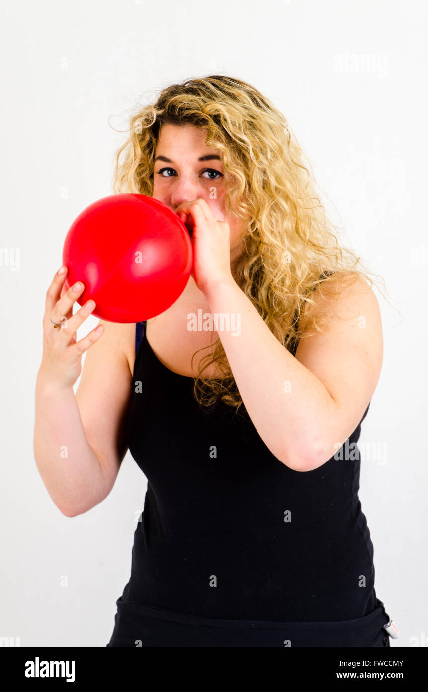 Unica femmina adulta che soffia su di medie dimensioni palloncino rosso Foto Stock