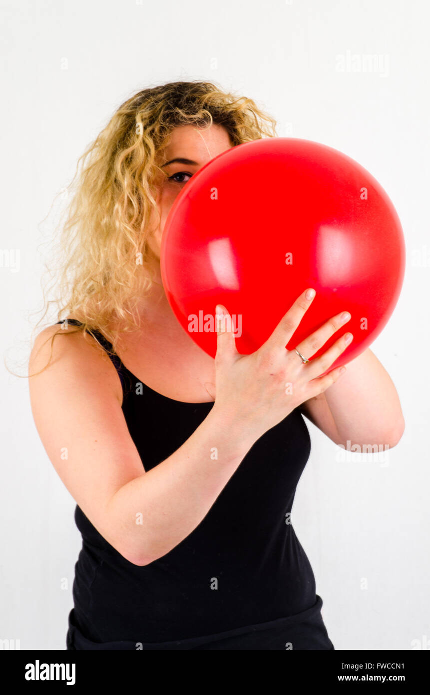 Unica femmina adulta che soffia su di medie dimensioni palloncino rosso Foto Stock