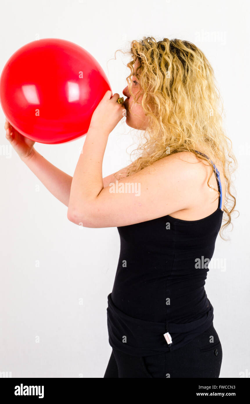Unica femmina adulta che soffia su di medie dimensioni palloncino rosso Foto Stock