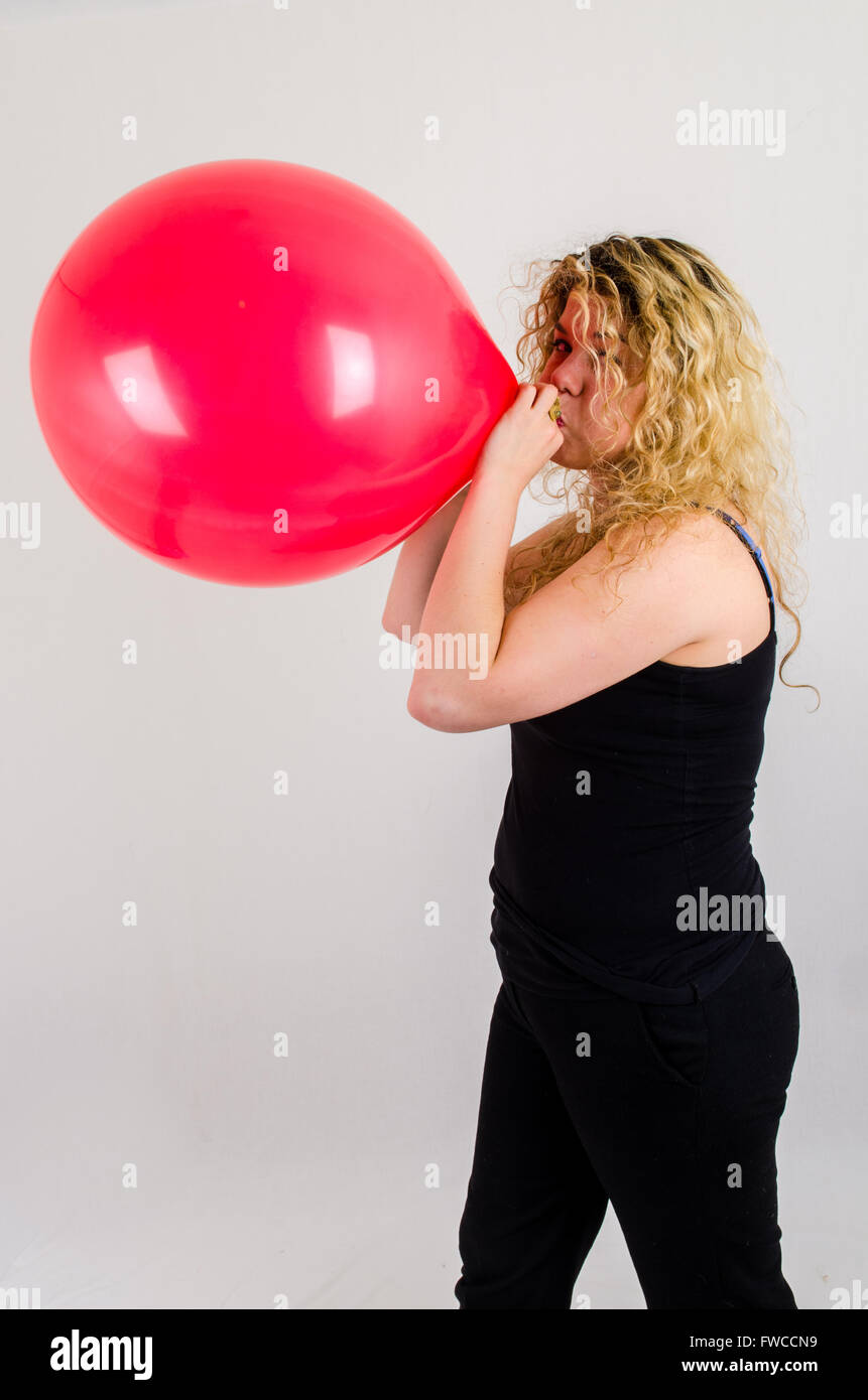Unica femmina adulta che soffia su di medie dimensioni palloncino rosso Foto Stock