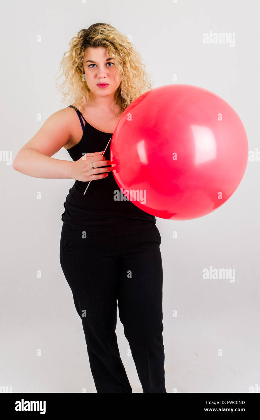 Unica femmina adulta che soffia su di medie dimensioni palloncino rosso Foto Stock