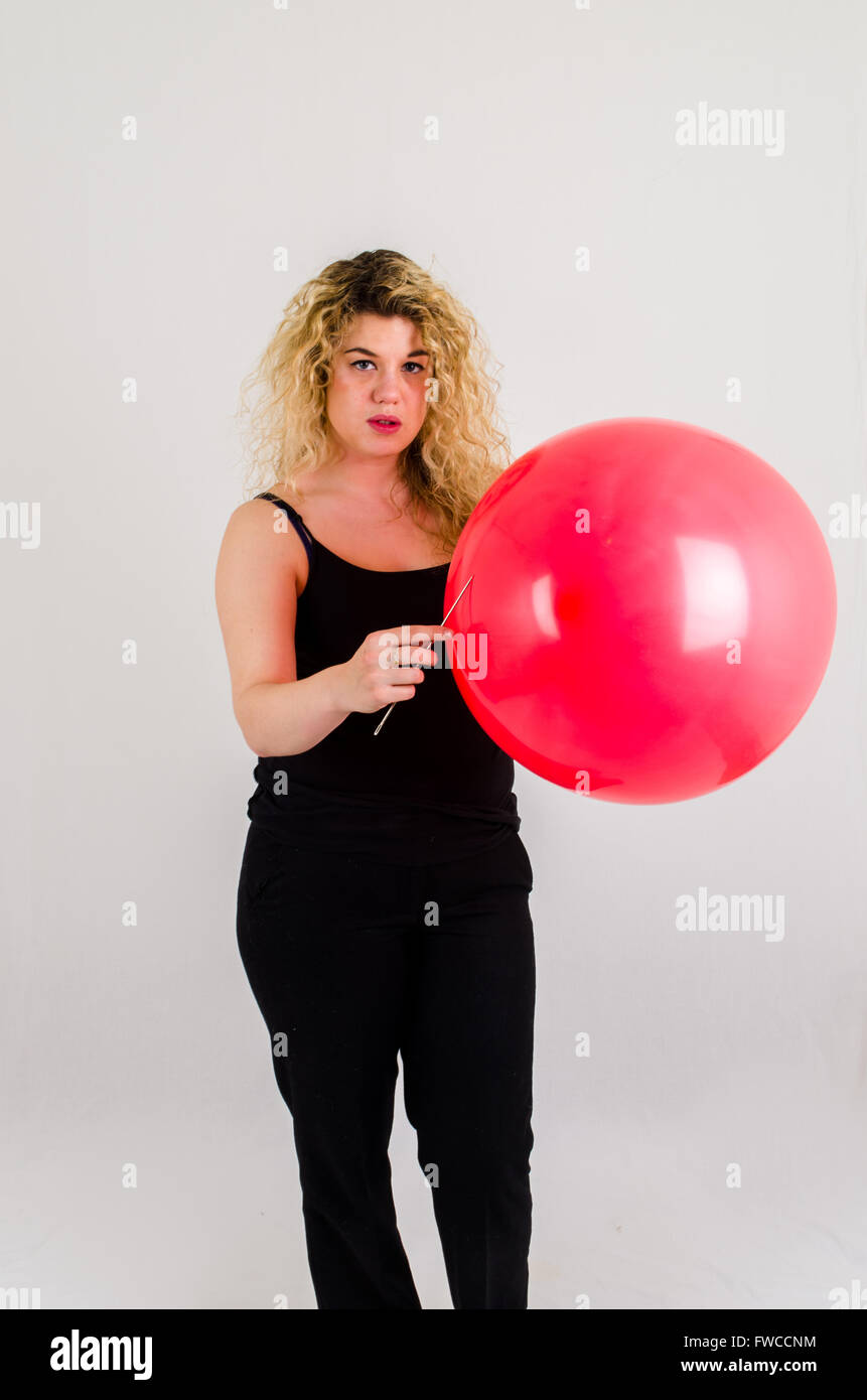 Unica femmina adulta che soffia su di medie dimensioni palloncino rosso Foto Stock