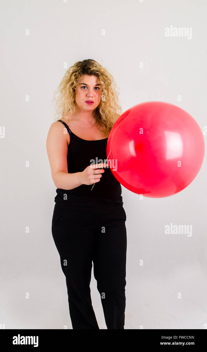 Unica femmina adulta che soffia su di medie dimensioni palloncino rosso Foto Stock