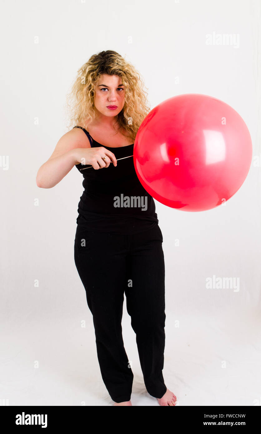 Unica femmina adulta che soffia su di medie dimensioni palloncino rosso Foto Stock