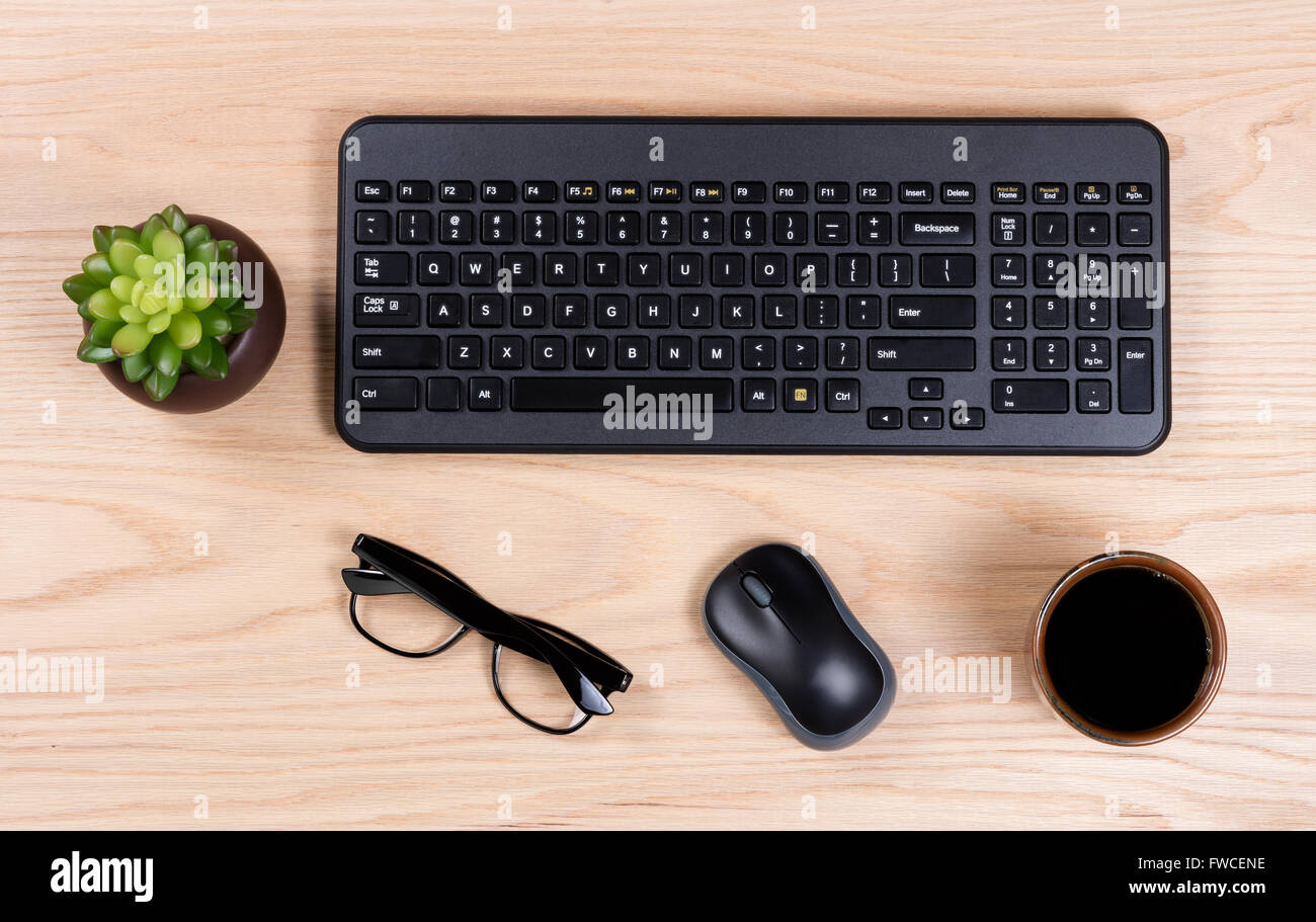 Vista aerea di una Scrivania pulita costituito da tastiera del computer, neonato impianto, mouse, caffè e gli occhiali da lettura. Foto Stock