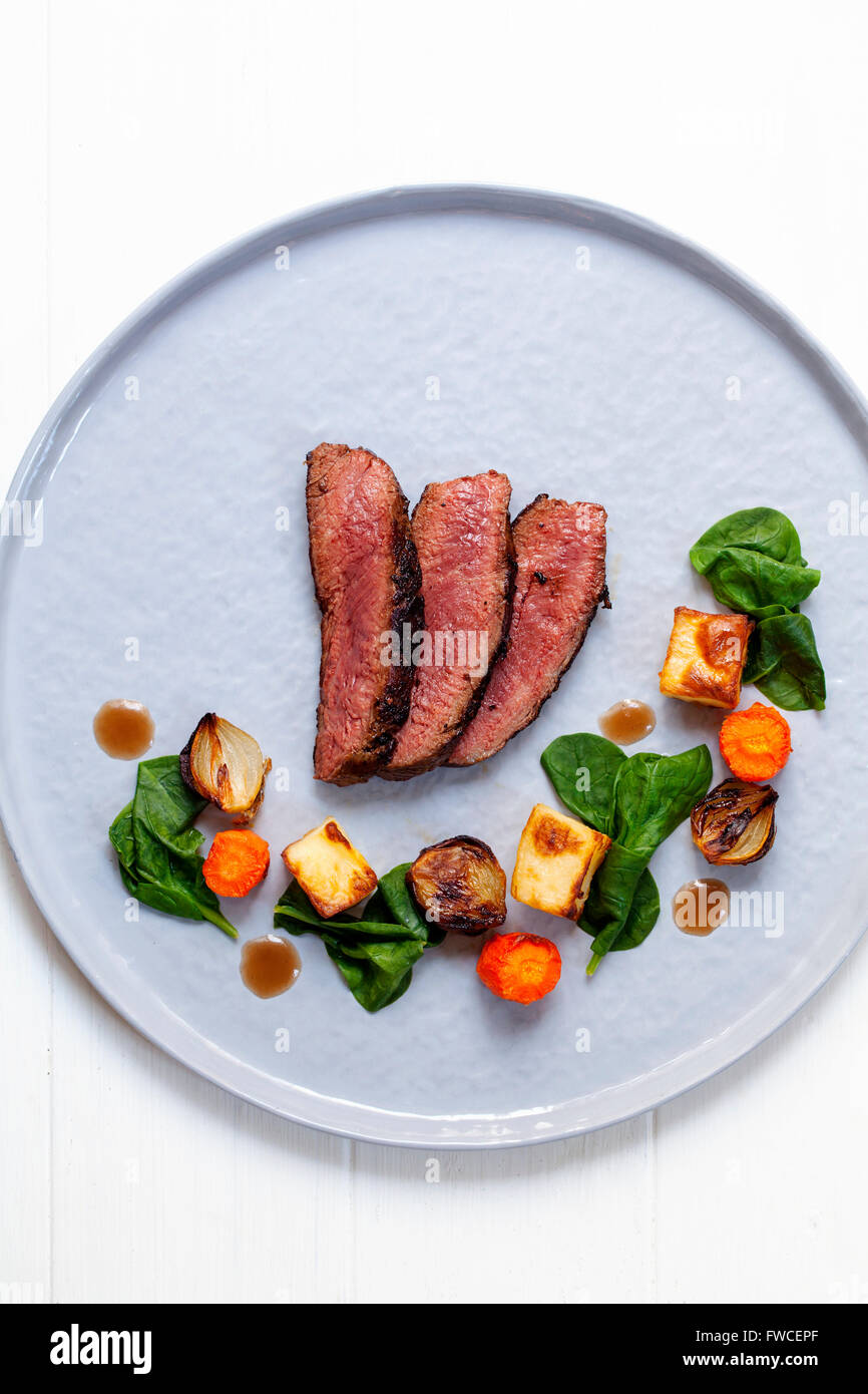 Fette di filetto di manzo con spinaci appassito, patate, carote e scalogni Foto Stock