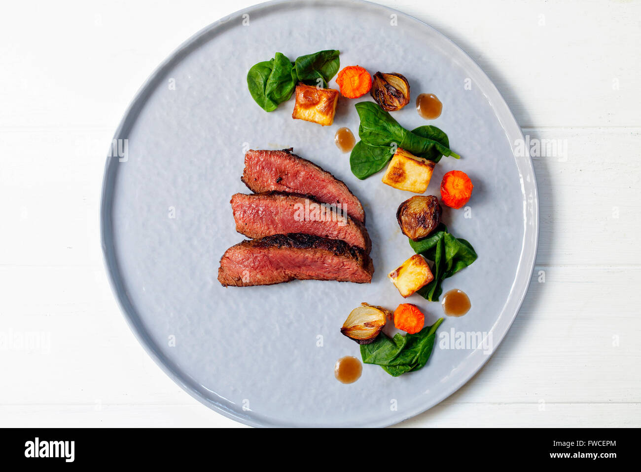 Fette di filetto di manzo con spinaci appassito, patate, carote e scalogni Foto Stock