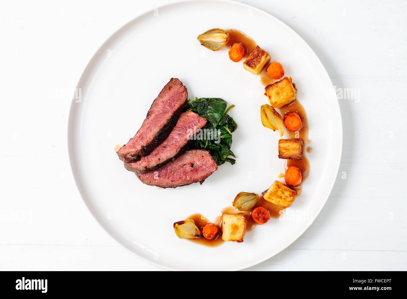 Fette di filetto di manzo con spinaci appassito, patate, carote e scalogni Foto Stock