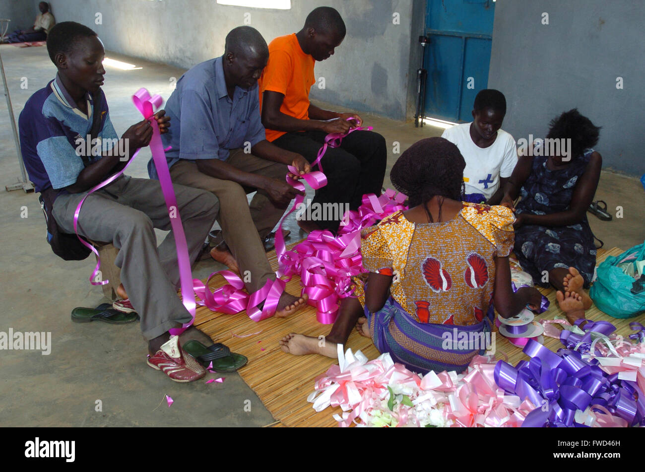 Lacekocot, distretto di Pader, Uganda. 2009. Gli uomini e le donne nella chiesa al Lacekocot sfollati interni nel campo di Pader rendere nastri e addobbi floreali per un matrimonio. La chiesa fu costruita per la trib Acholi che vivono sul campo e mettere in pratica il cristianesimo. Il gruppo di sedersi su un coloratissimo tappeto sul pavimento di cemento. Foto Stock