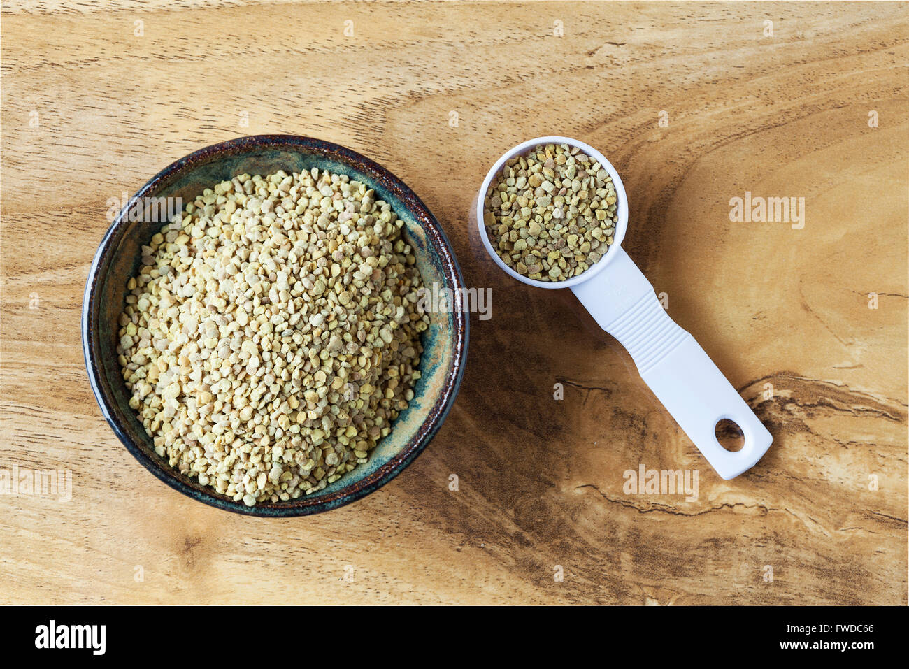 Polline di api nel recipiente di ceramica e misurino su un tavolo di legno. Vista da sopra con copia spazio. Foto Stock