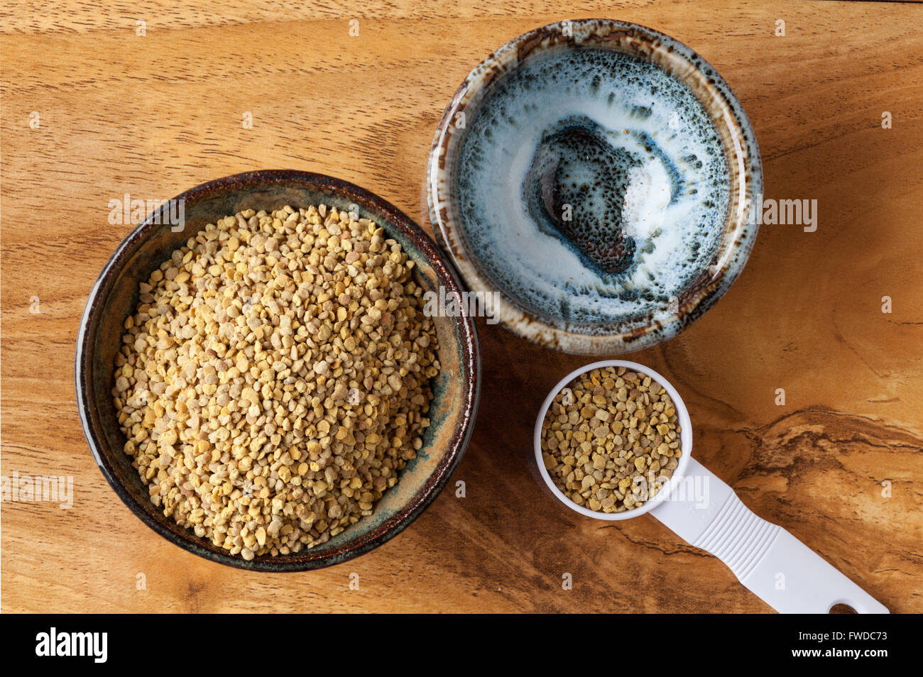 Polline di api nel recipiente di ceramica e misurino su un tavolo di legno. Vista da sopra con copia spazio. Foto Stock