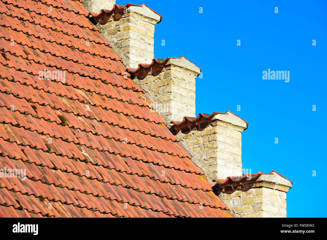 Incantevoli dettagli architettonici di una vecchia casa di mattoni dove la facciata di colore giallo incontra il tetto di tegole rosse e. Foto Stock